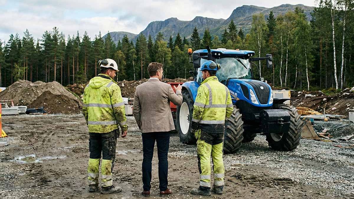 Tre menn i diskusjon på anleggsområde