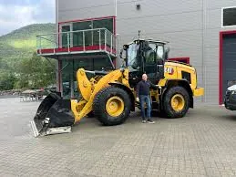 Gul hjullaster parkert foran et moderne kontorbygg med en person ved siden av.